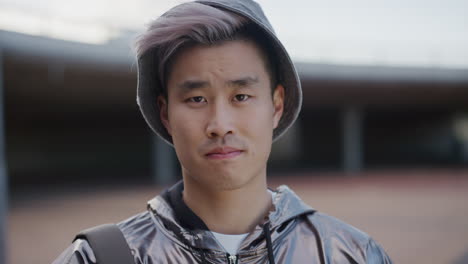 retrato de cerca hombre joven asiático guapo buscando serio independiente estudiante de sexo masculino con sombrero de moda de moda en el fondo urbano