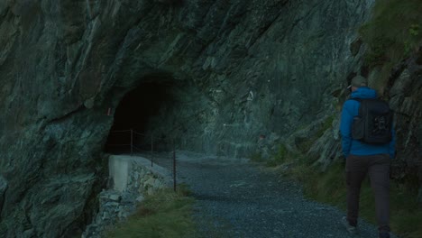 man walking towards cave tunnel in rocky mountain near cima fontana, valmalenco, italy