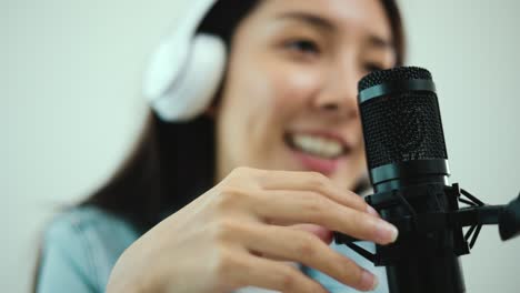 close-up condenser microphone of content creator woman host streaming his a podcast on laptop with headphones interview conversation at home broadcast studio. blogger recording voice over radio.