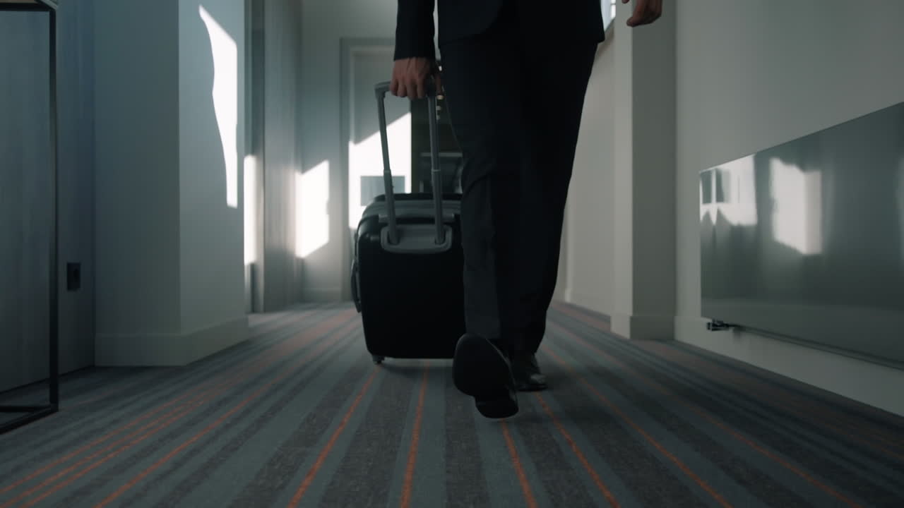Business man legs with travel suitcase walking at hotel corridor