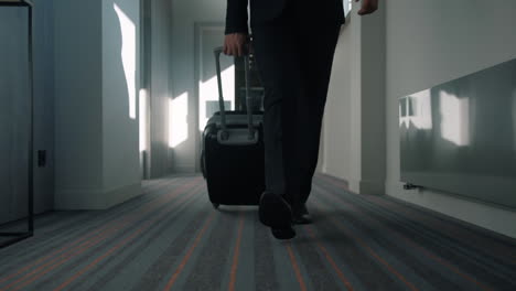 business man legs with travel suitcase walking at hotel corridor