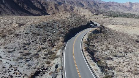 Public-bus-transporting-passengers-on-highway-74-in-deserted-area,-aerial-drone-shot