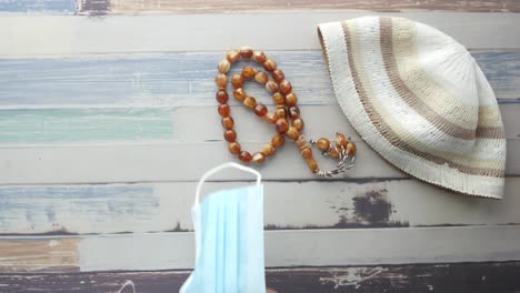 gorra de oración musulmana, cuentas de oración y máscara en una mesa de madera
