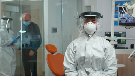 Dentist-in-coverall-looking-and-smiling-at-camera