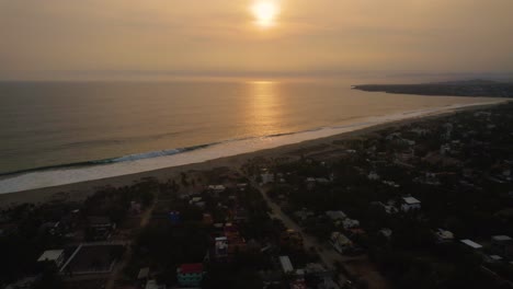 Volando-Sobre-La-Ciudad-Hotelera-De-Puerto-Escondido-En-México-Para-Revelar-El-Paisaje-Marino-Caribeño-Con-La-Puesta-De-Sol-En-El-Fondo