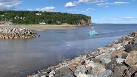 A-long-wide-pan-of-a-fishing-boat-arriving-at-Alma-Harbour-in-New-Brunswick-on-a-sunny-day