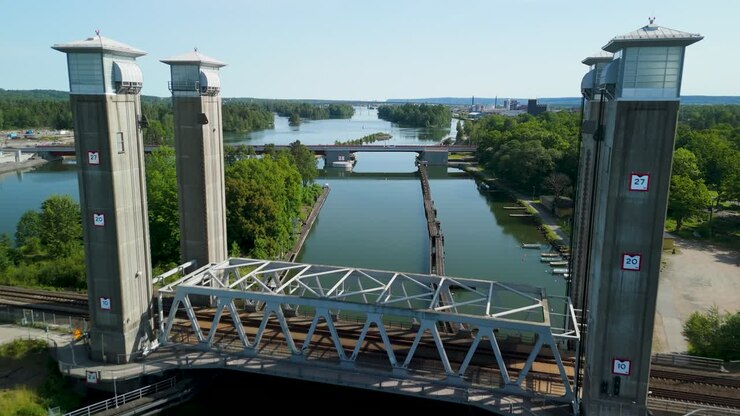 Un drone sorvola lo storico ponte ferroviario a traliccio metallico sul fiume Gota Alv per rivelare il nuovo ponte Stridsbergsbron e lo skyline urbano durante una soleggiata mattina estiva in Svezia
