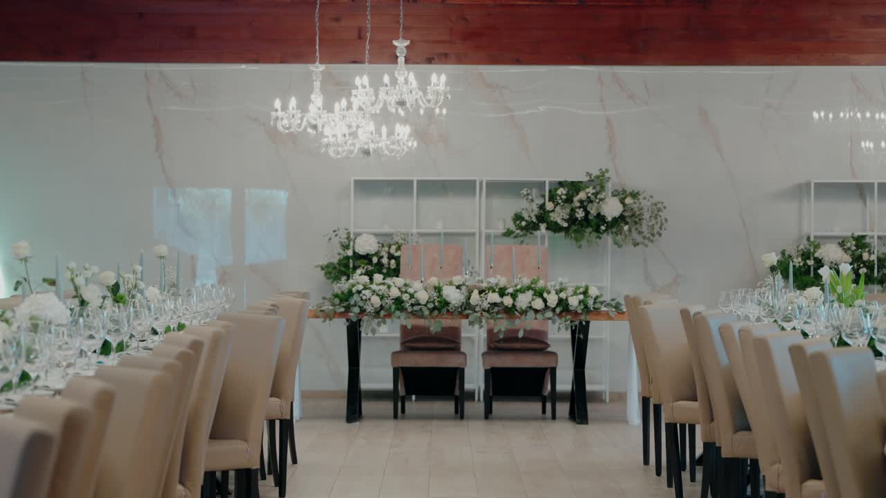 Luxurious wedding reception hall with floral decorations, chandeliers, and banquet seating