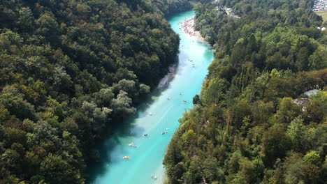 Aerial-drone-shot-of-people-at-a-festival,-swimming-and-playing-in-a-river-in-Slovenia