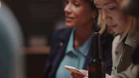 young asian woman using smartphone in restaurant texting on social media  sharing reunion party with friends having fun evening