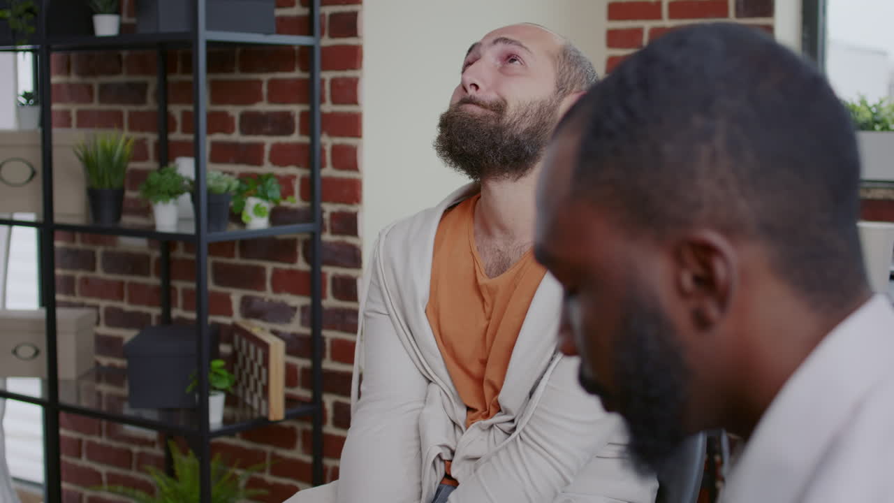 Close up of sad man crying and sharing story about alcohol addiction with people at aa meeting