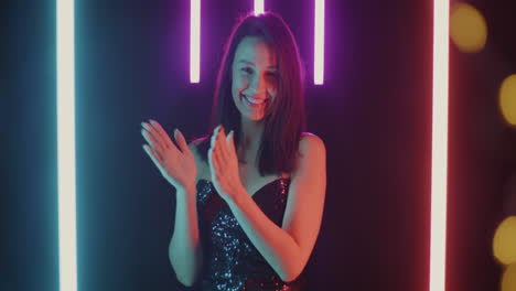 woman celebrating with clapping hands in neon lights