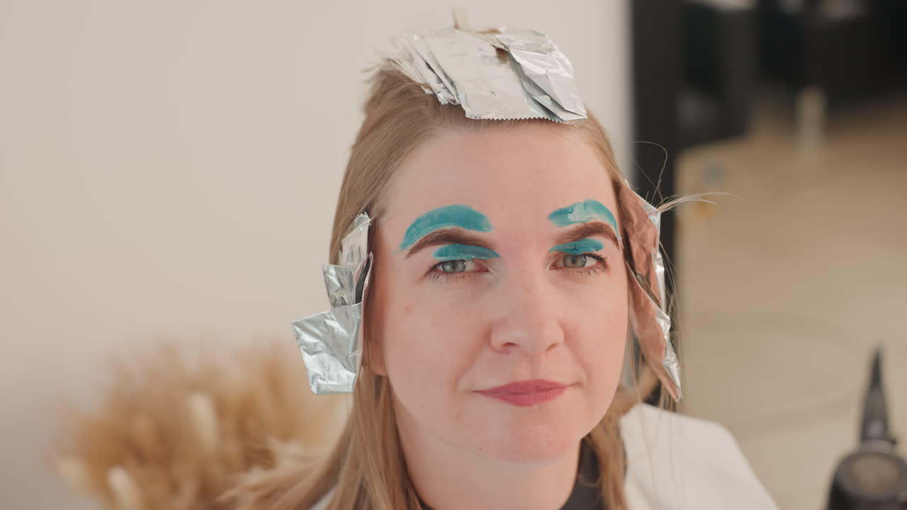 white woman with foil and teal eyebrow makeup in closeup reveal frontal and topdown angles showing processed highlights, playful confident smile, editorial test for social content, stylist tools