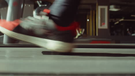 feet of man walking on treadmill in gym