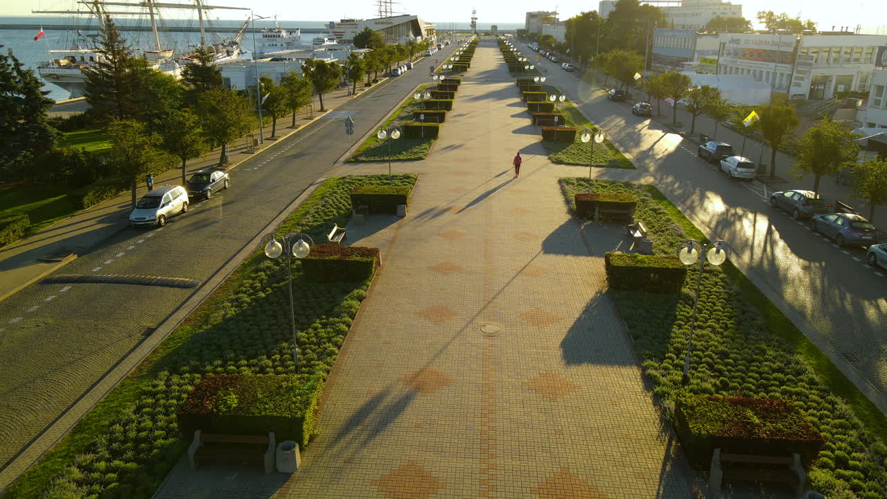 Aerial view of beautiful promenade with pedestrian and bikes beside port of Gdynia with parking ships