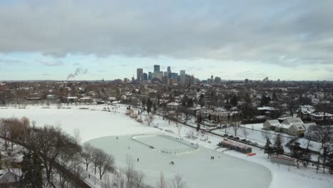 people skating on frozen pond with minneapolis skyline in background