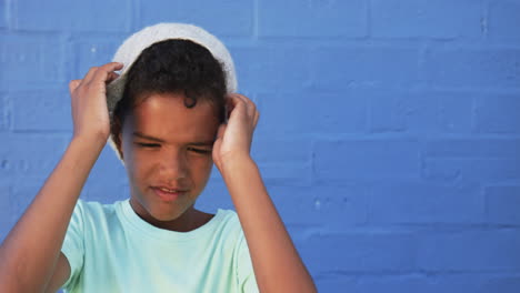 un joven estudiante biracial está de pie contra un fondo azul, copia el espacio