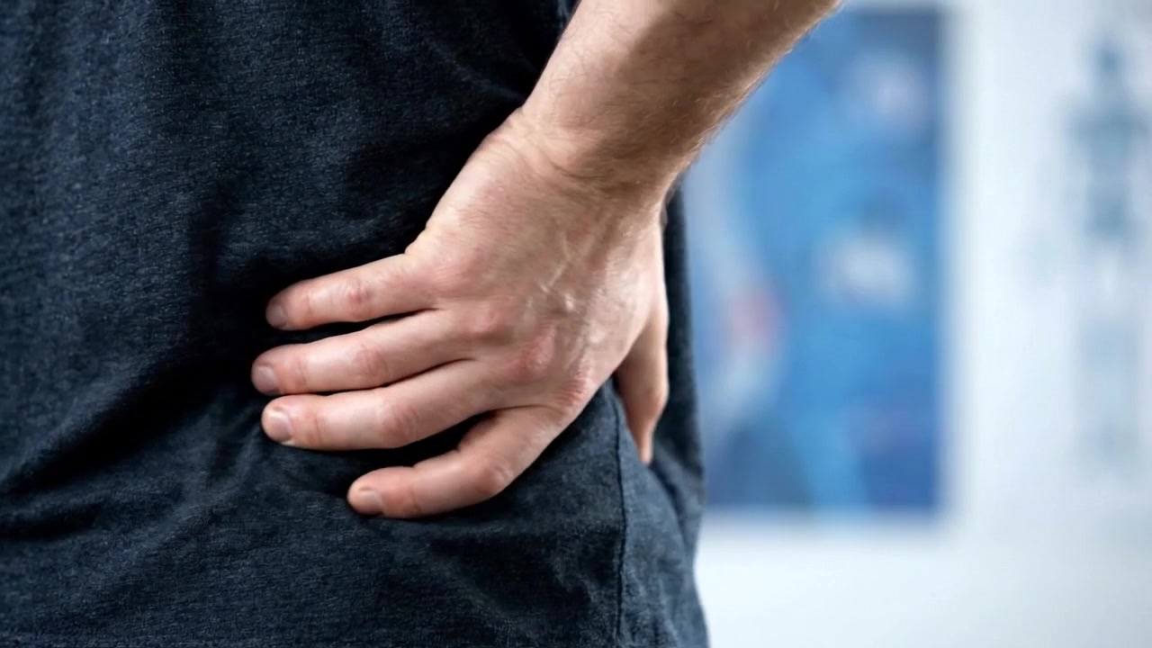 Man Holding His Lower Back in Pain at a Medical Clinic