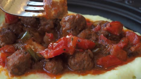 close up of meatballs and mashed potatoes with red pepper and tomato sauce