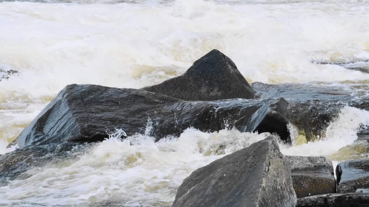Slow motion shot of powerful white water flowing over sharp rocks