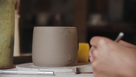 young woman potter making ribs for attaching a handle to a cup made out of clay