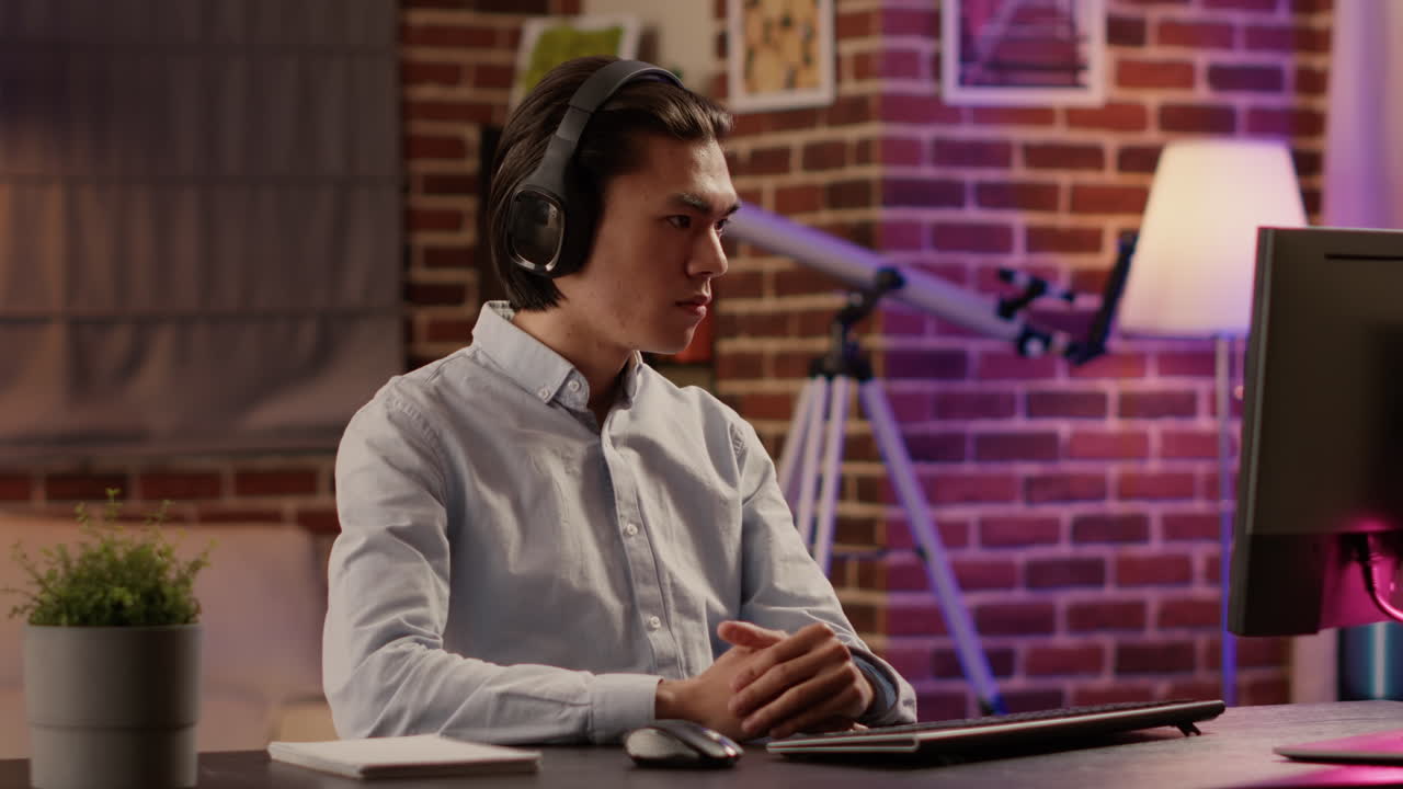 Man wearing headphones using computer at desk
