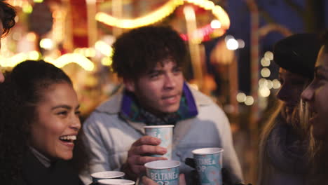 group of friends drinking mulled wine at christmas market