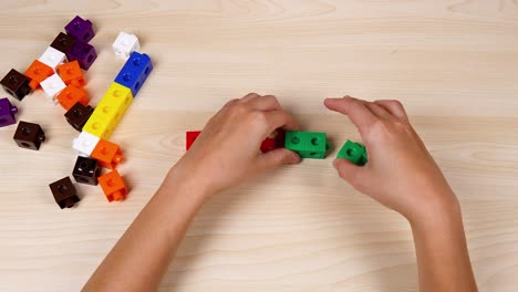 hands assembling colorful cubes on a table