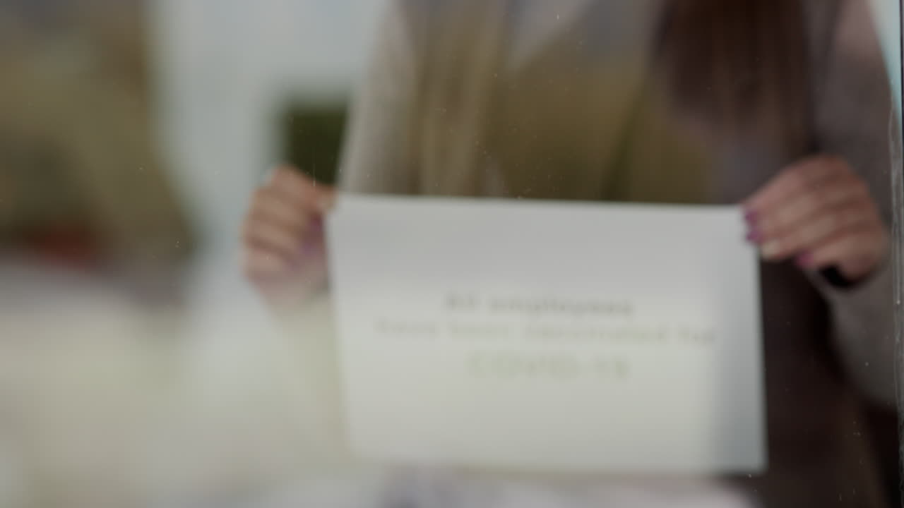 직원이 모든 직원이 예방 접종을 받고 안전하게 방문한다는 안내 문구를 식당 문에 걸고 있습니다.