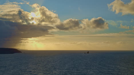 Stunning-seascape-from-Cligga-Head-as-sunset-rays-pierce-clouds,-wide