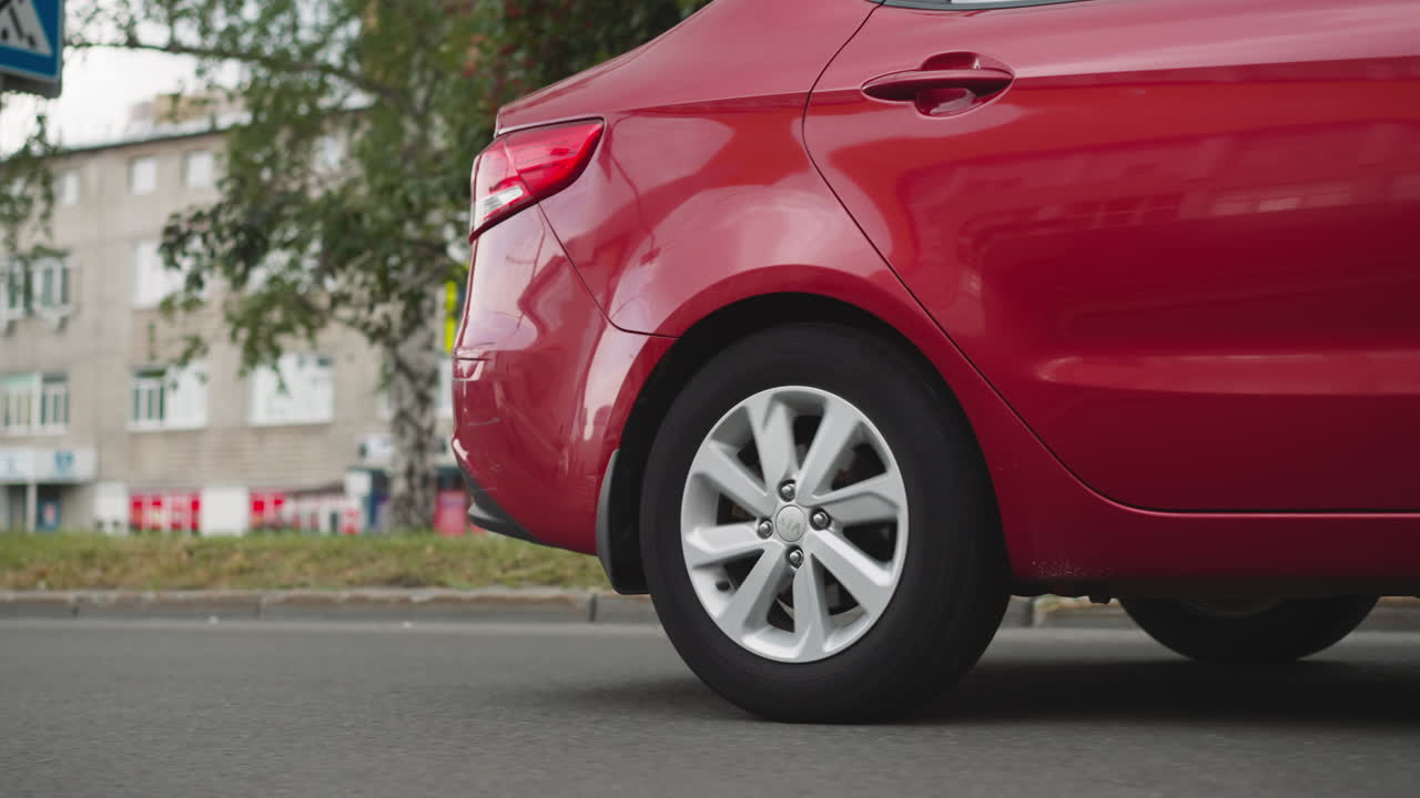 el sedán rojo conduce por la calle vacía pasando por edificios viejos