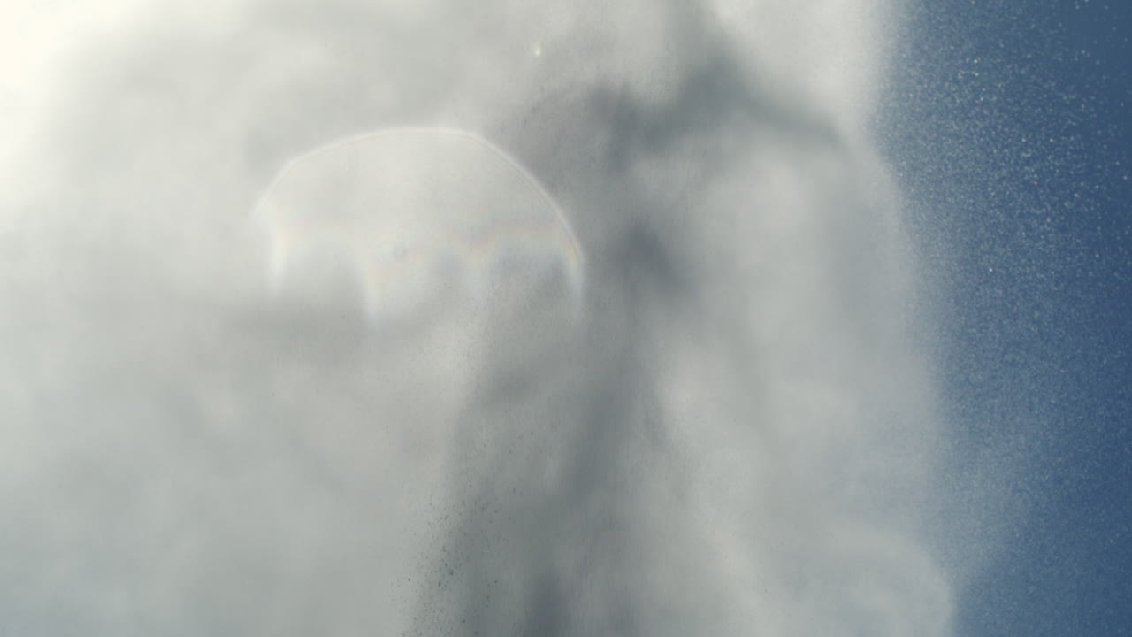 Water surge shoots into sky forming smooth arc of foam in soft bright daylight scene