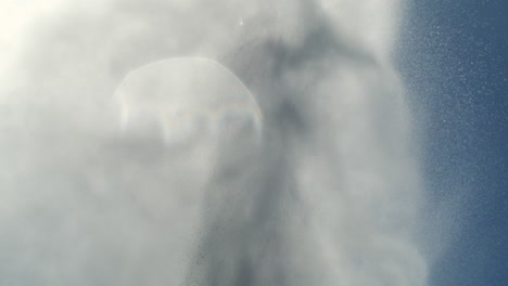 water surge shoots into sky forming smooth arc of foam in soft bright daylight scene