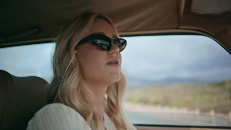 stylish blonde girl driving road in sunglasses closeup. woman focused on roadway