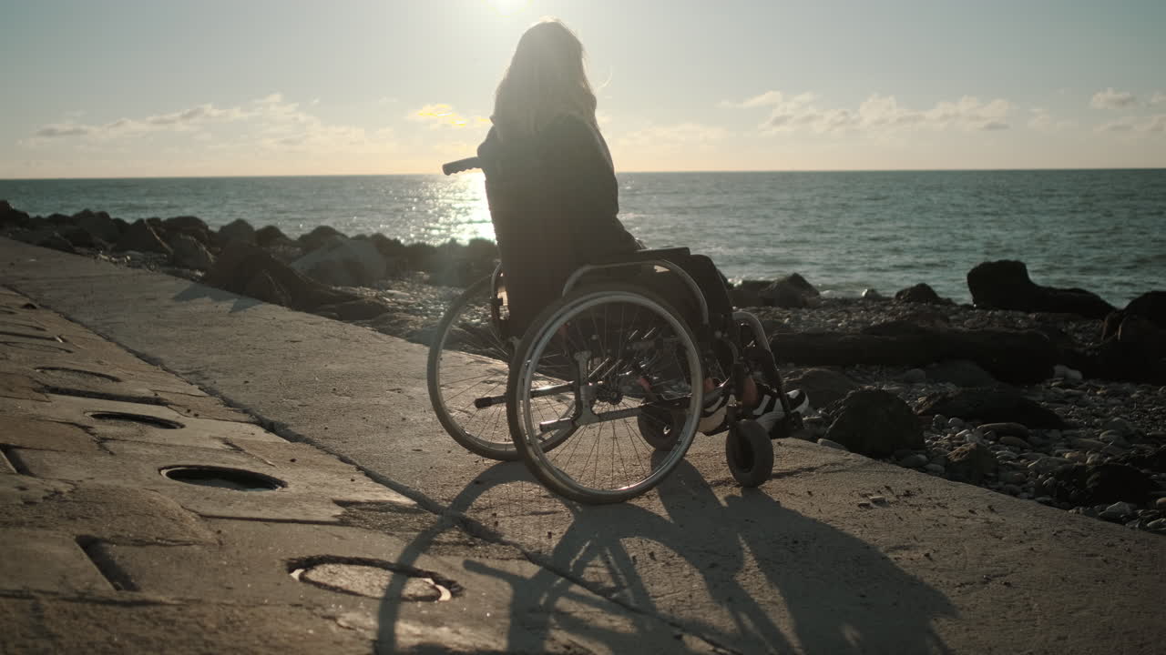 mujer en silla de ruedas en la playa del atardecer