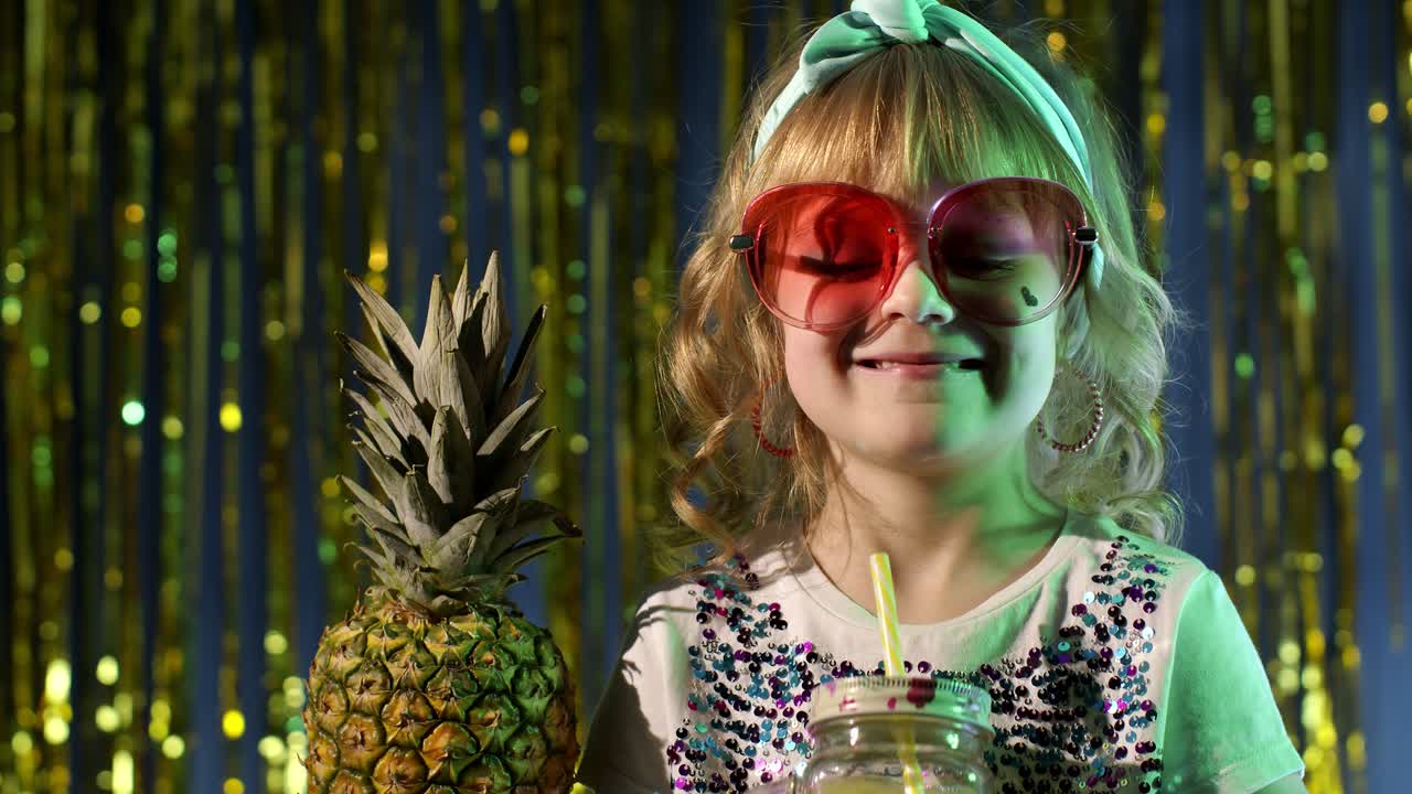 niño a la moda con frutas de piña bebiendo jugo en un club futurista con luz de neón