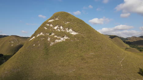 flying towards the green mountain on a sunny summer day in sumba island, indonesia