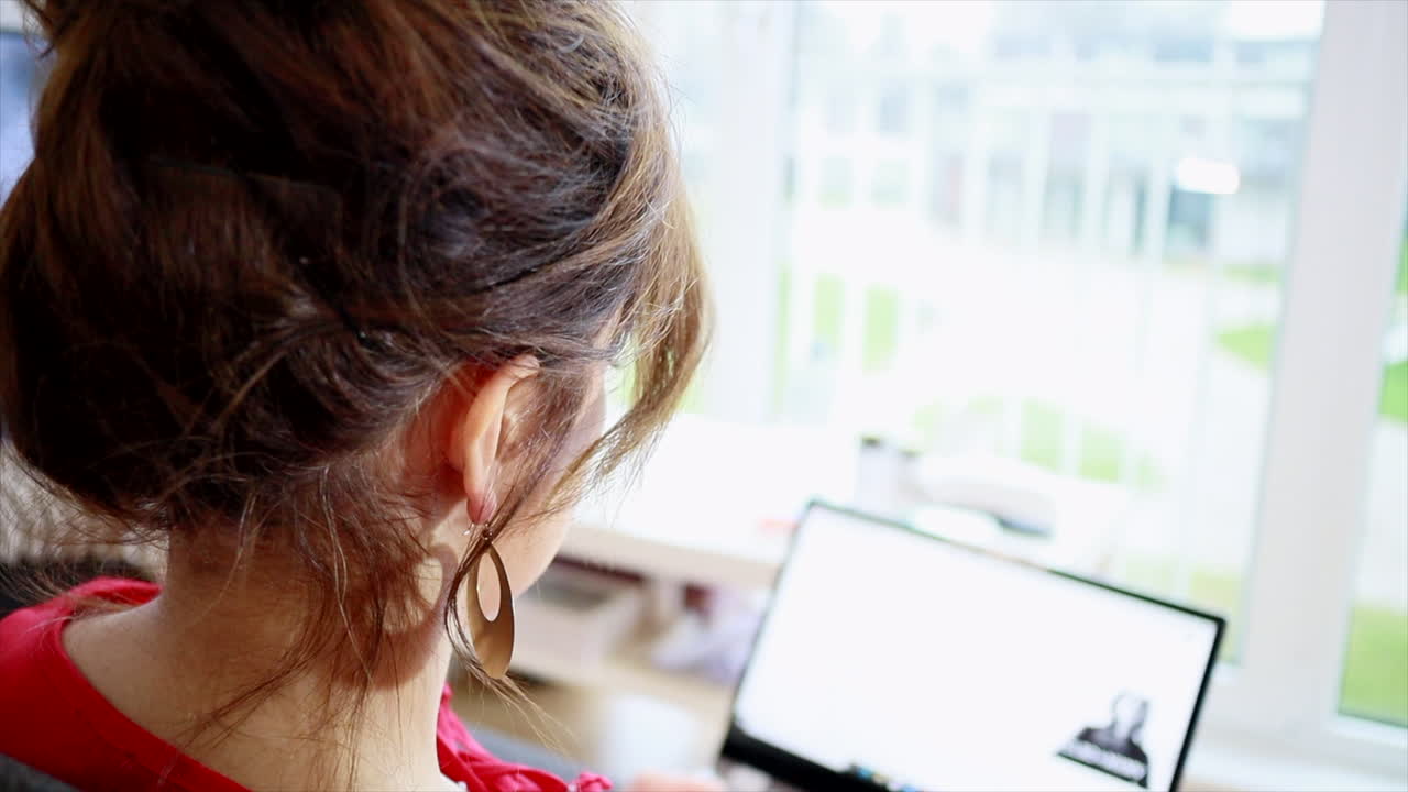 Back View Of A Woman With Gold Earrings Scrolling On Laptop Screen - selective focus