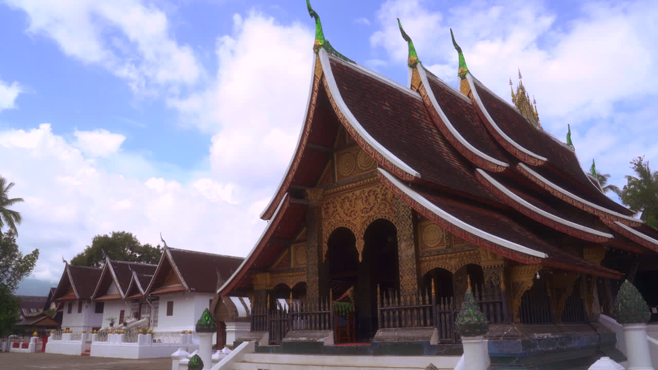 Ornate Buddhist temple roof and facade in Luang Prabang, Laos under sunlight, frontal establishing medium