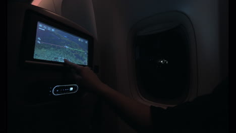 woman looking at plane route on seat monitor