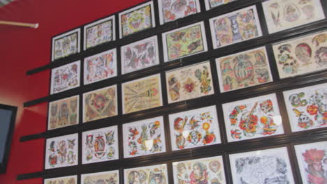 footage of a wall of framed tattoo designs at a tattoo shop.