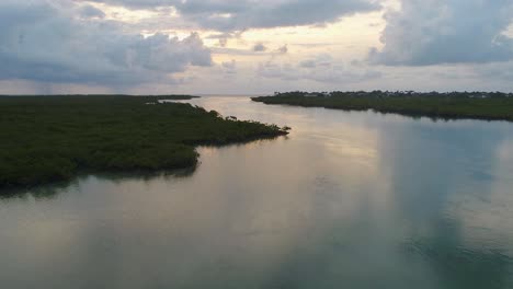 A-low-flying-drone-shot-over-the-clear-blue-water-cutting-through-the-unique-mangrove-environment-during-sunrise,-near-Islamorada-of-the-Florida-Keys,-USA