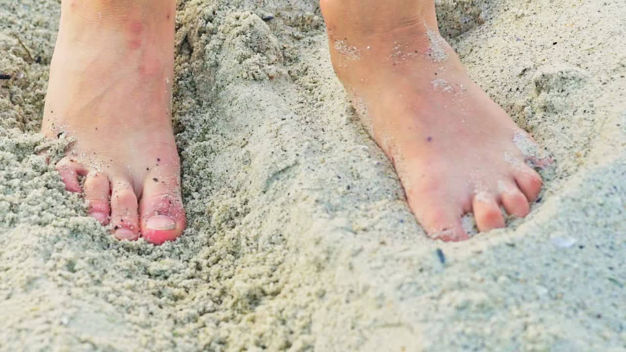 Feet of a human are rummaging sand on the beach in the summer in warm weather. Sandy shore. Rest on the sea.