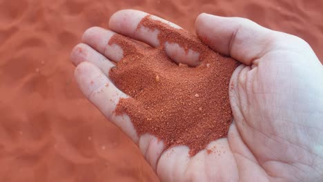 Roter-Sand-Der-Wadi-Rum-Wüste-Läuft-Durch-Die-Finger,-Nahaufnahme-Einer-Handvoll-Sand-In-Jordanien,-Naher-Osten