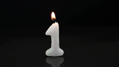 abstract red decorative shapes over number one birthday burning candle against black background