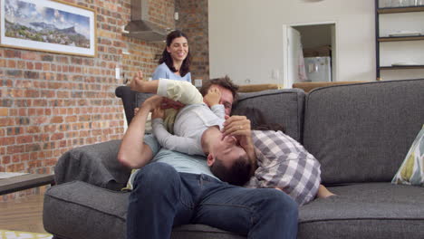 father plays with children as mother works on laptop