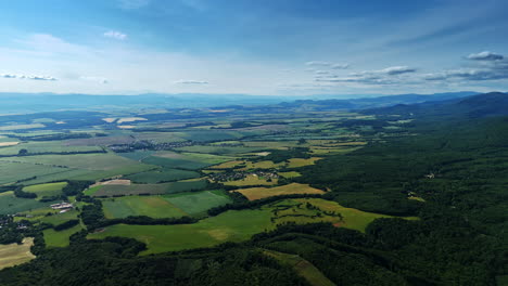 vast mountain countryside view. green fields stretch towards distant mountains under a clear blue sky, showcasing nature's tranquil beauty and vastness