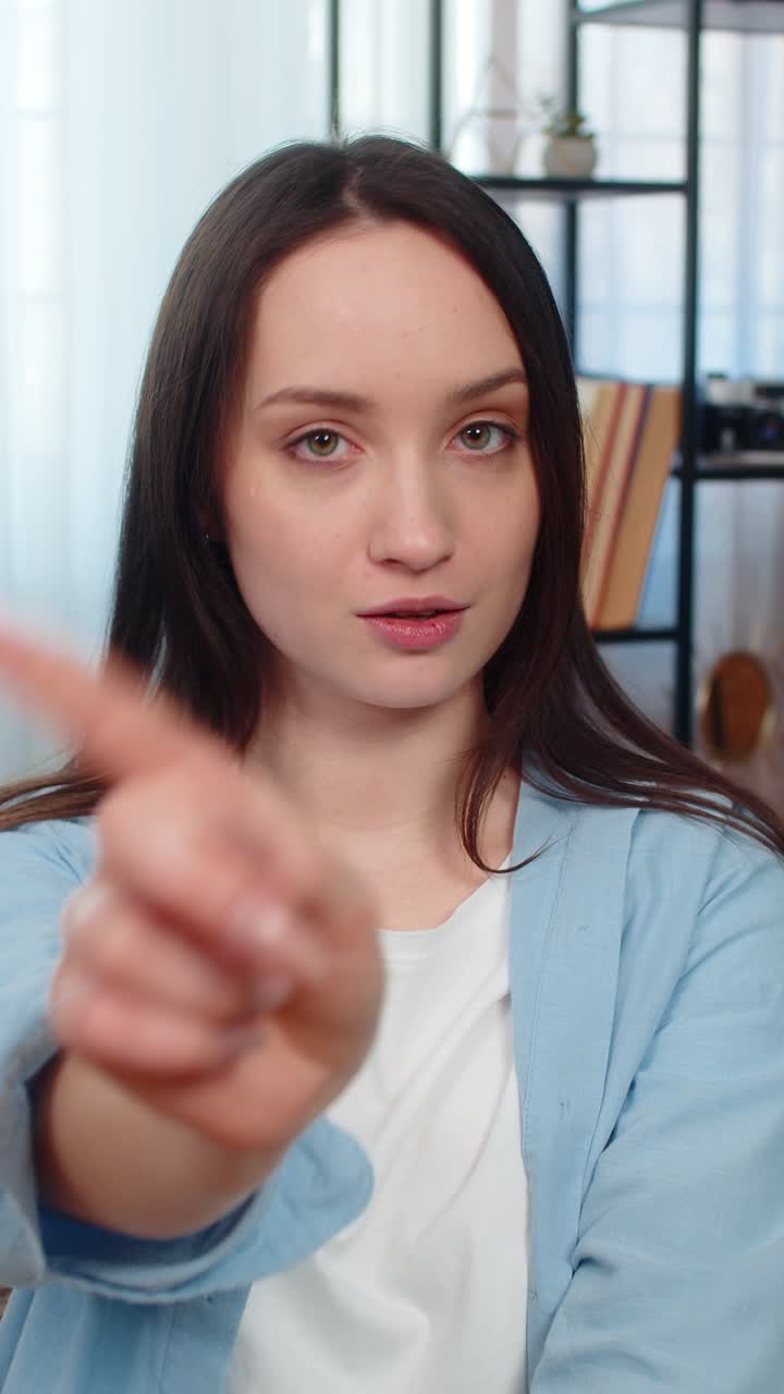 Young woman on sofa waving finger gesture no disagreeing unhappy dissatisfied facial expression