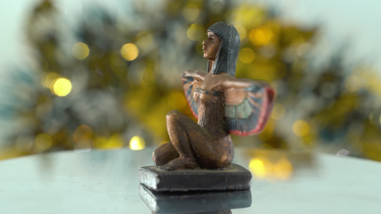 un primer plano de ensueño de una estatua de cleopatra con alas de pájaro abiertas, profundidad de campo dorada brillante, gobernante histórico egipcio, obra de arte antigua de una diosa, girando 360 vídeo cinemático estático 4k