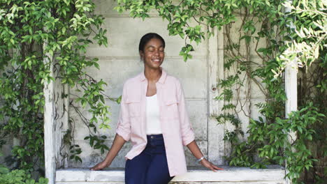 a young african american woman smiles in a leafy alcove